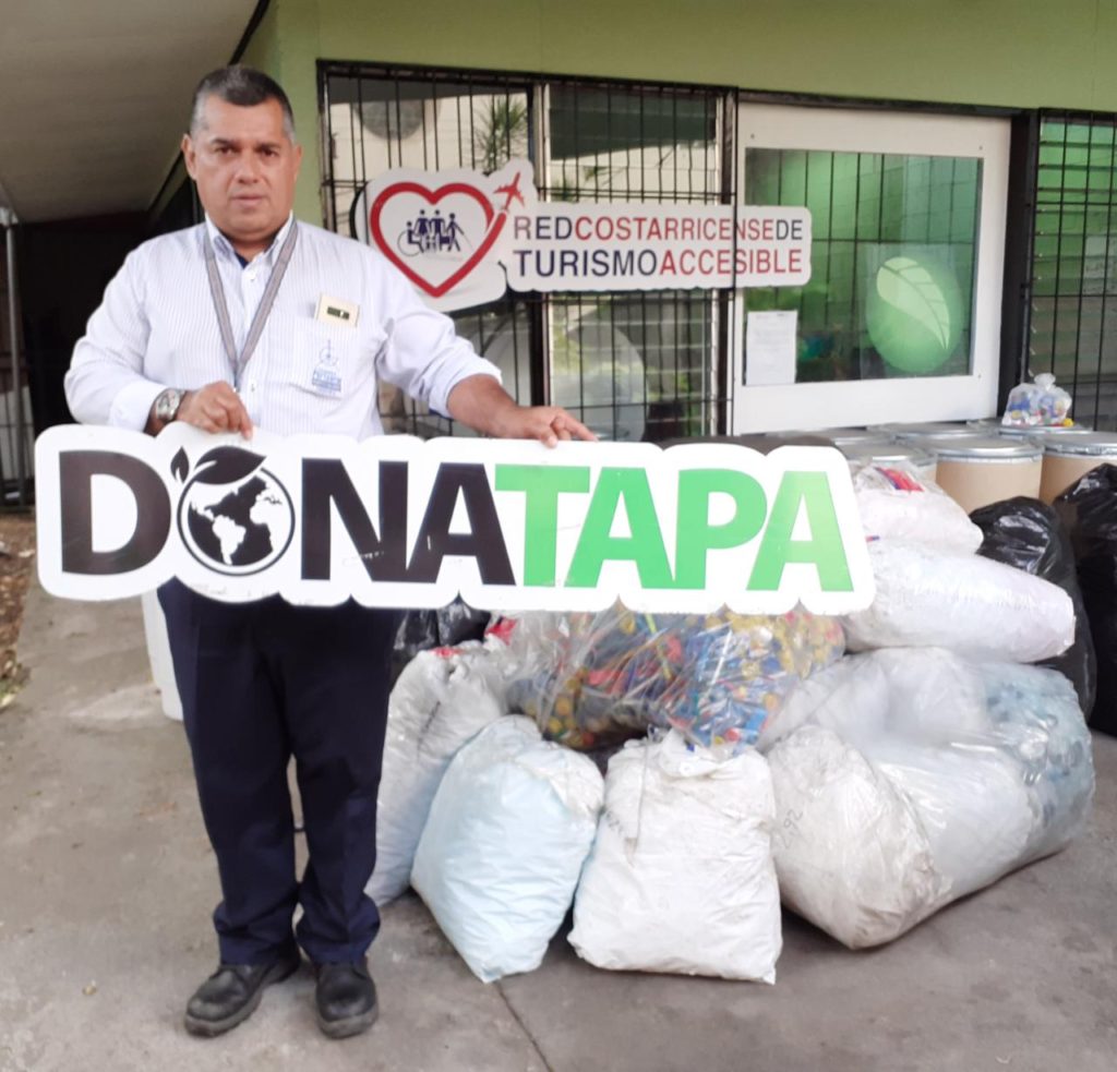 Hombre con rótulo de Donatapa y bolsas llenas de tapas, haciendo entrega en nuestra oficina